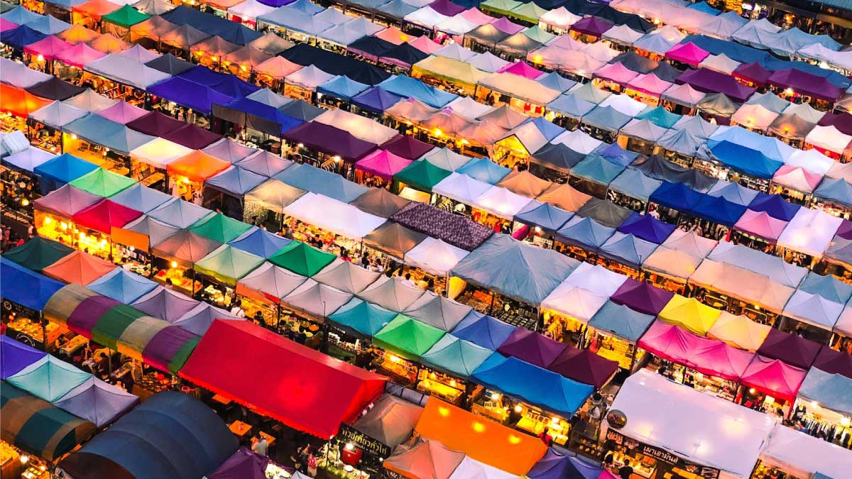 Aerial view of a colorful night market with rows of vendor tents, used as a concept for emerging apparel sourcing markets.